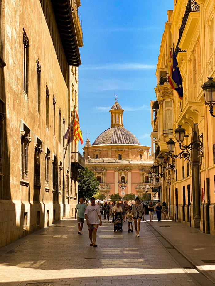 People walking through a narrow historic street in Valencia, Spain