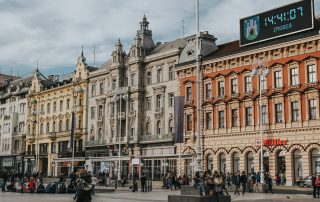 A vibrant view of Ban Jelačić Square in Zagreb, featuring historic buildings, the equestrian statue of Ban Jelačić, and people enjoying the lively city atmosphere