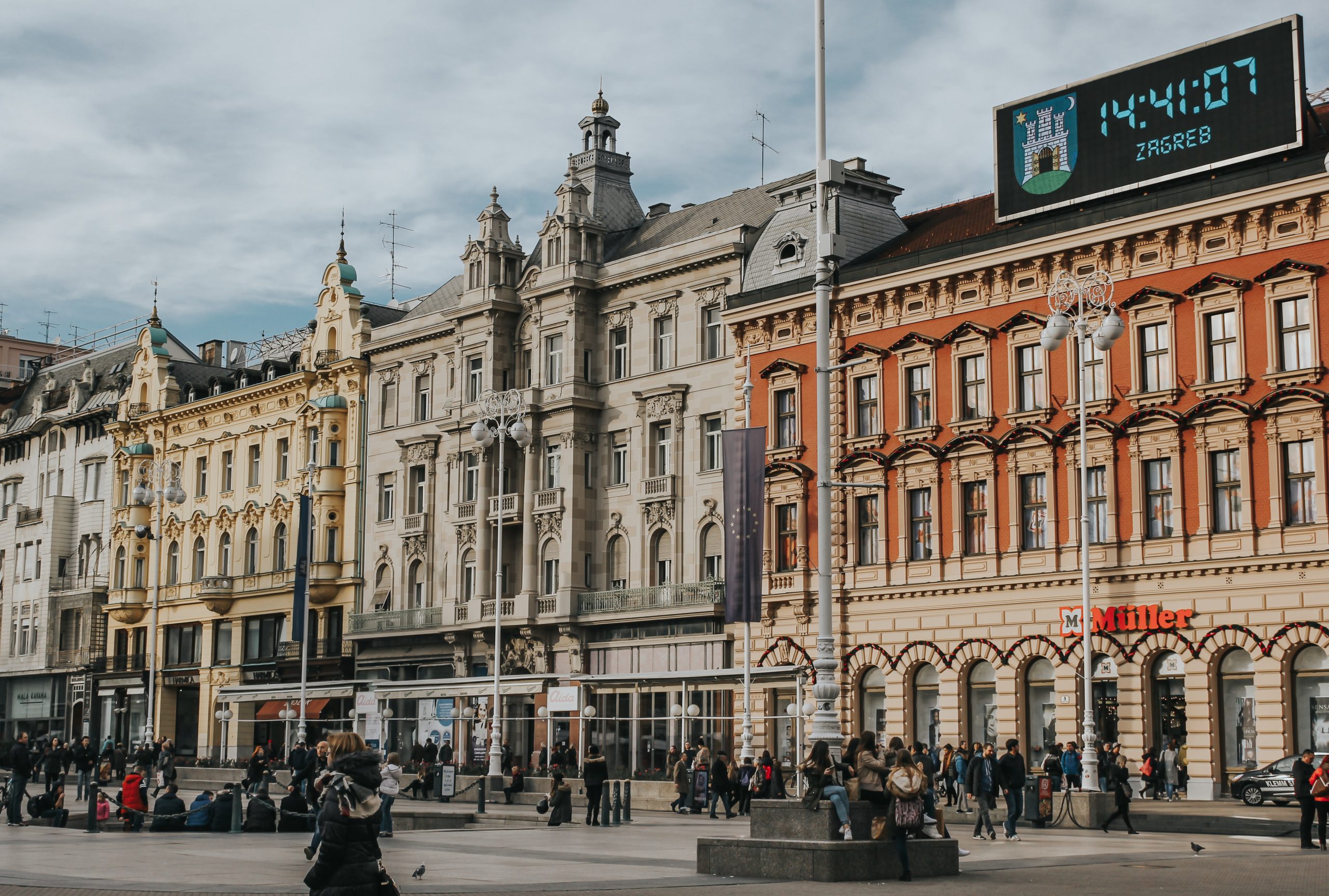 A vibrant view of Ban Jelačić Square in Zagreb, featuring historic buildings, the equestrian statue of Ban Jelačić, and people enjoying the lively city atmosphere