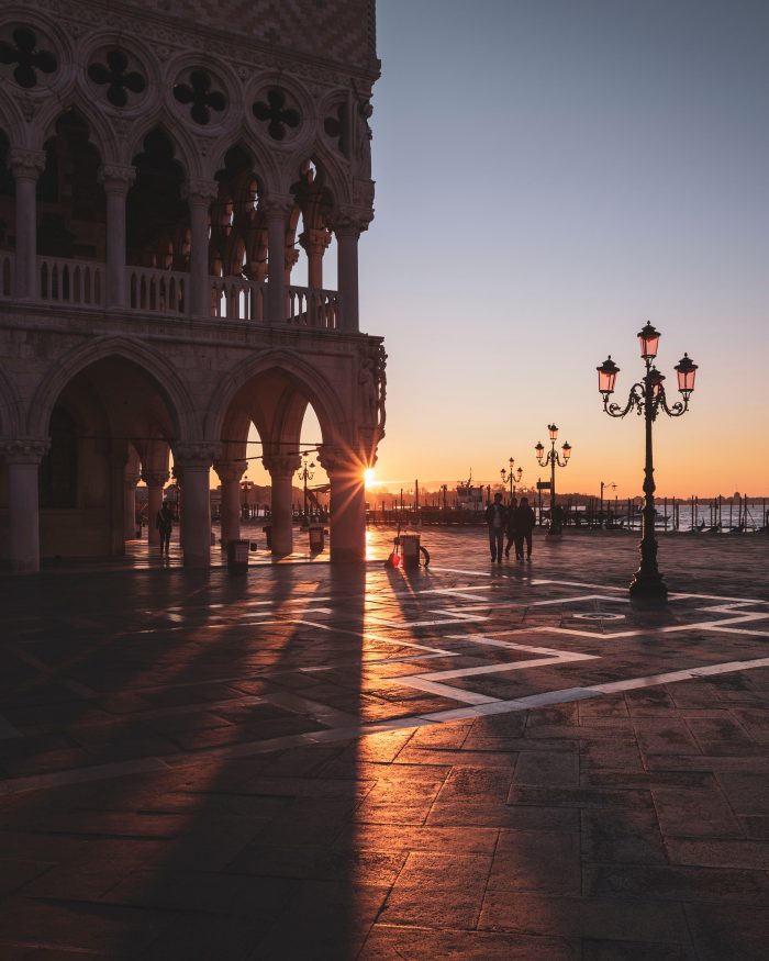 Golden sunset over Venice with glowing skies reflected on the canals and silhouettes of historic buildings