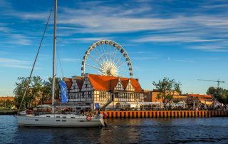 A historic ship docked in the port of Gdańsk, Poland, with old town architecture in the background