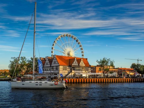 A historic ship docked in the port of Gdańsk, Poland, with old town architecture in the background