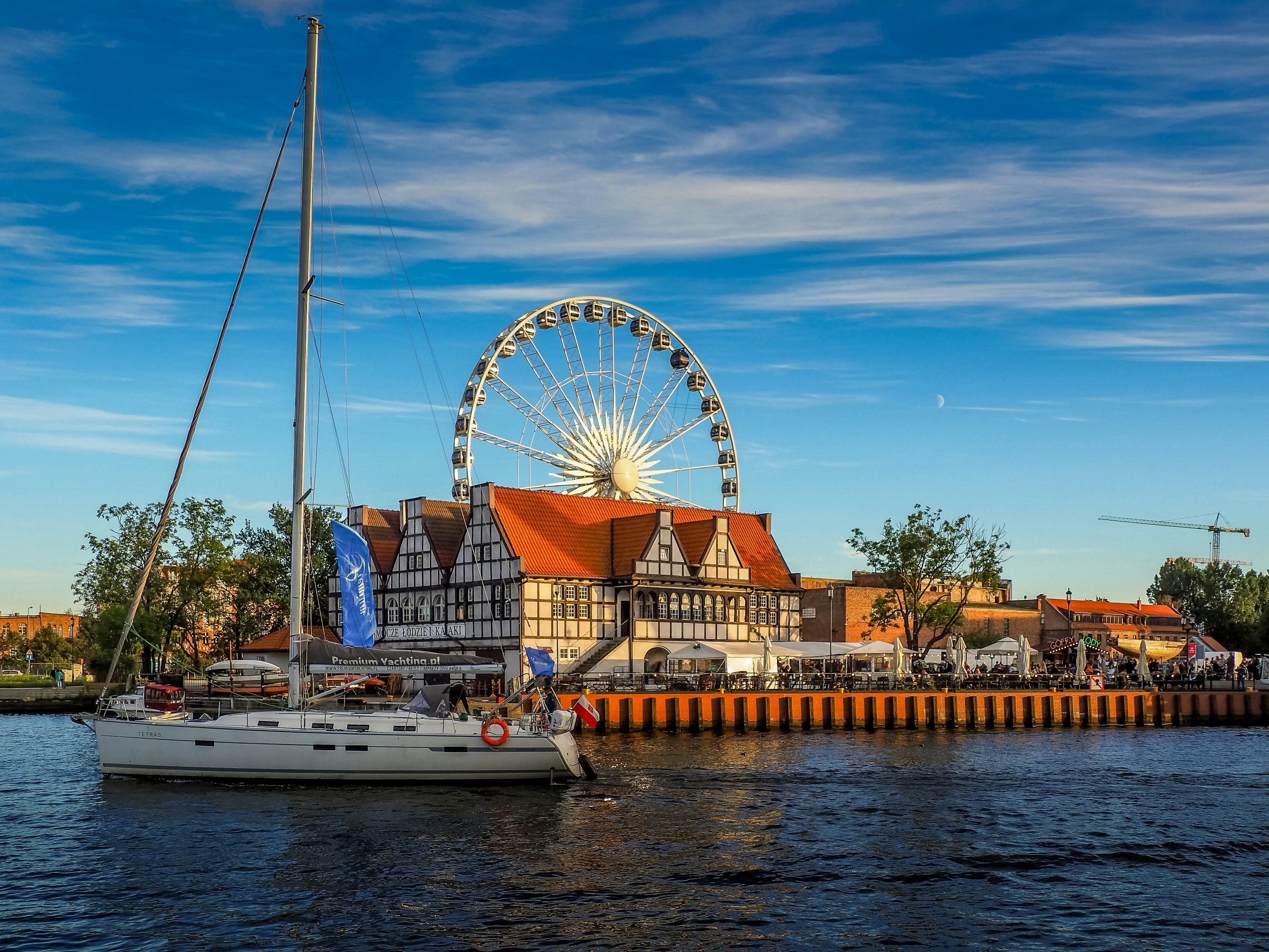 A historic ship docked in the port of Gdańsk, Poland, with old town architecture in the background
